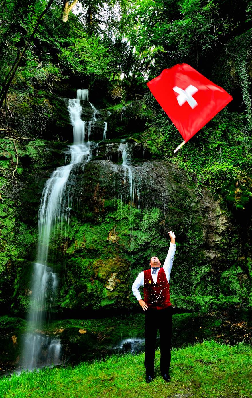 Flag thrower with Swiss flag in front of a waterfall