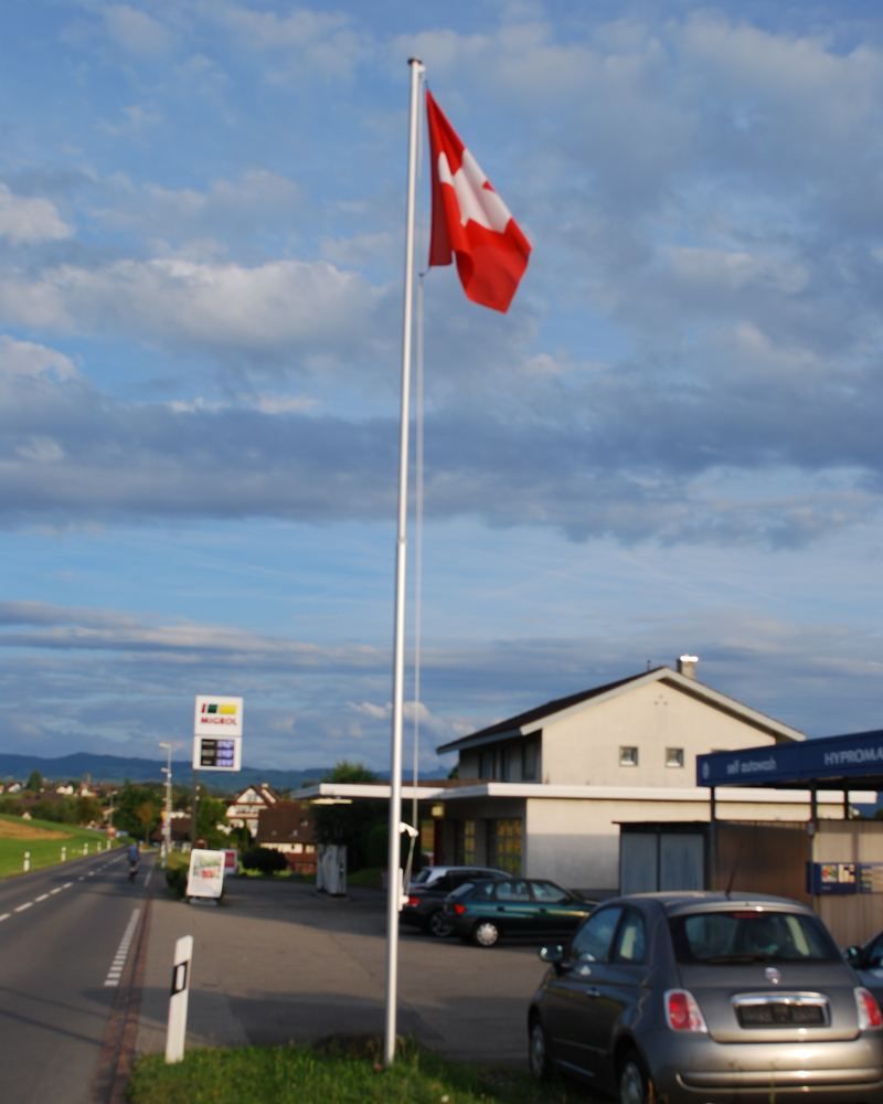 Deluxe Fahnenmast aus Aluminium mit Schweizerfahne, eingebaut an der Strasse
